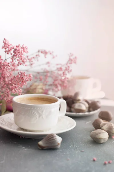 Шоколадные конфеты в форме ракушки и две чашки ароматного кофе. Романтический завтрак. Светлые цвета. Розовые цветы. Свободное место для текста. копией пространства — стоковое фото